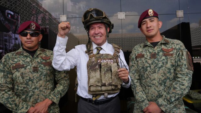 Ricardo Monreal porta chaleco y casco tácticos junto a dos militares durante una exhibición.